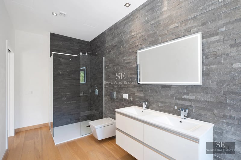 Image of a luxurious pool with sun loungers and umbrellas, surrounded by a modern house with large windows and lush vegetation.