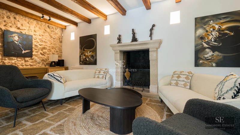 Spacious, bright living room with fireplace, leather sofa, coffee table, and large windows overlooking the garden. Modern and elegant design.