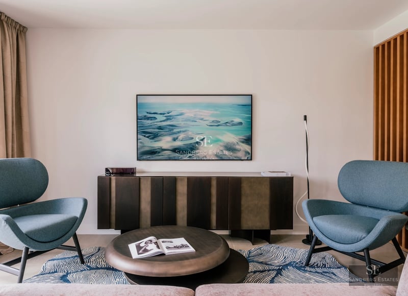 Spacious living room with large windows, panoramic sea views, modern furniture, and light wood floors.