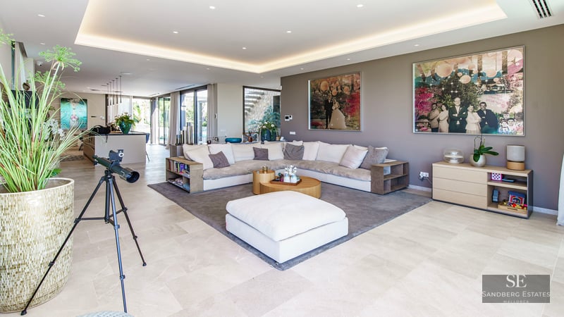 Vaste salon moderne avec canapé en L, télescope et art contemporain sous un éclairage de plafond encastré.