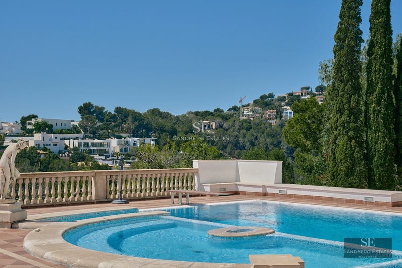 Exterior of a modern villa with infinity pool, lush garden and large terraces. Minimalist architectural design with large windows.