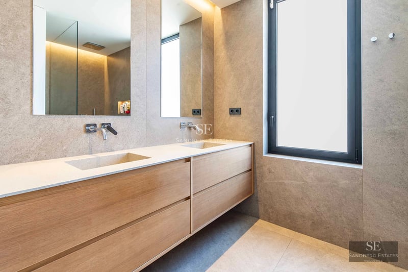 Spacious balcony with sea views. Glass railing, modern furniture, and wooden flooring. Minimalist design and abundant natural light.