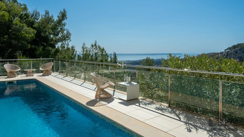 Expansive terrace with infinity pool, sun loungers, and panoramic sea views. Modern design with clean and elegant lines.