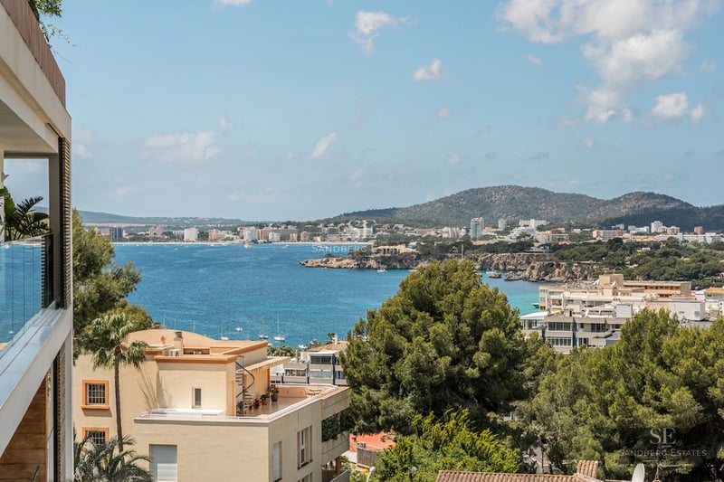 View of a luxury pool with lounge chairs and umbrellas in a manicured garden. Modern facade with large windows.
