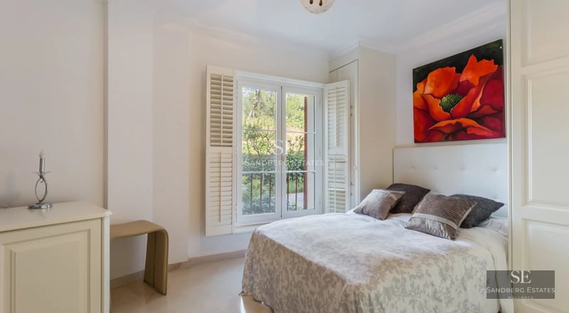 Large infinity pool surrounded by lawn and lush vegetation. Modern architecture with large windows and natural light.