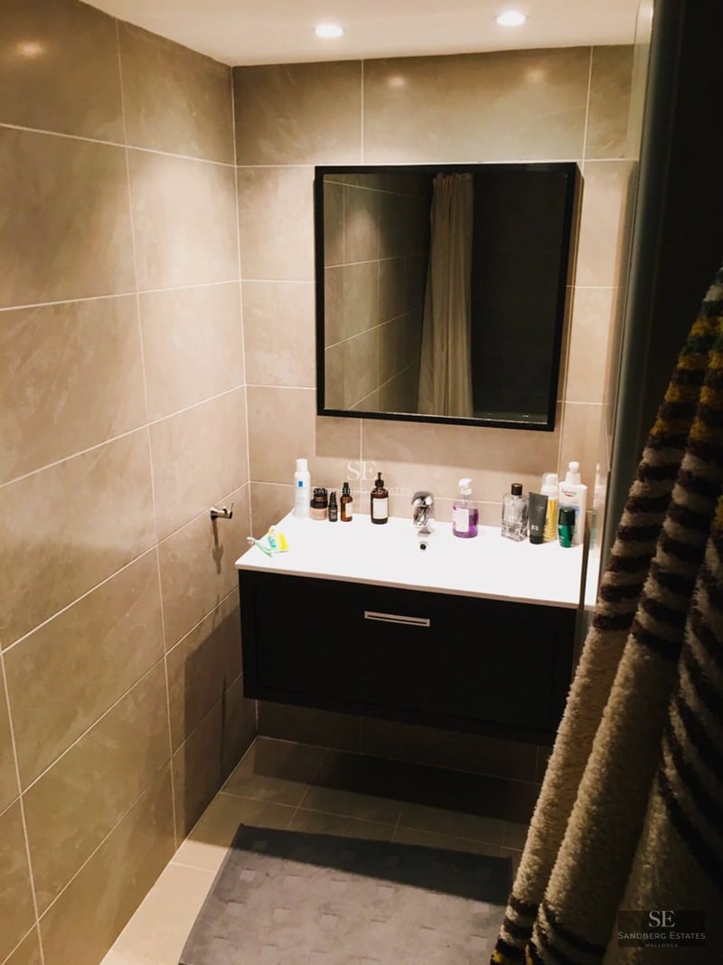 Grand balcon avec vue sur la mer, garde-corps en verre, plancher en bois et mobilier d'extérieur moderne. Design minimaliste et lumière naturelle abondante.