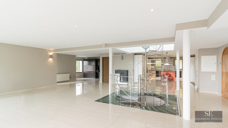 Large modern living area featuring polished marble floors and a central metal and glass spiral staircase.