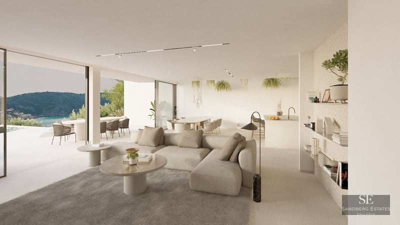Sunlit minimalist living room with beige sofa, marble tables, and large windows opening to a terrace with sea views.
