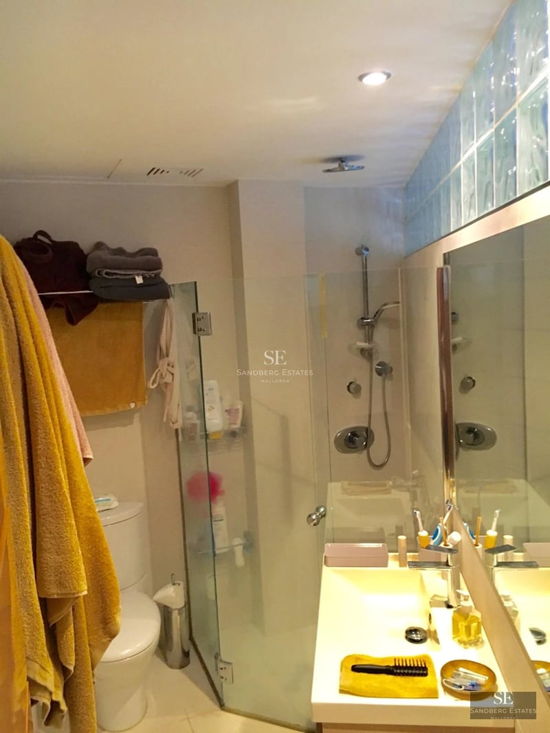 Large reflecting pool bordered by lawn and a modern villa with large windows reflecting sunlight.