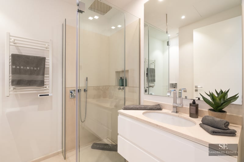 Modern bathroom featuring a glass walk-in shower, white vanity with chrome faucet, and a heated towel rack.