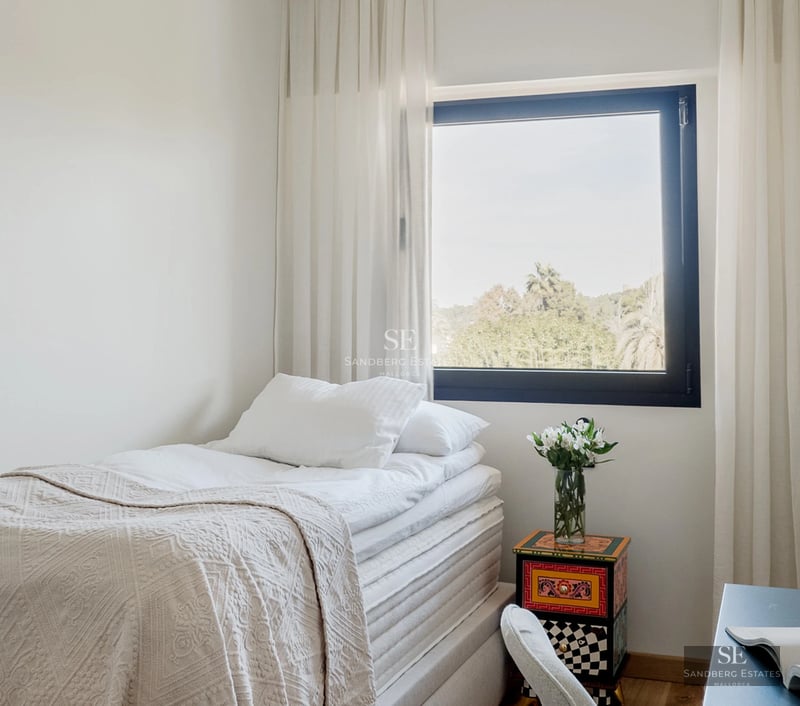 Exterior view of a modern villa with a pool, surrounded by greenery. Minimalist architectural design and large open spaces.