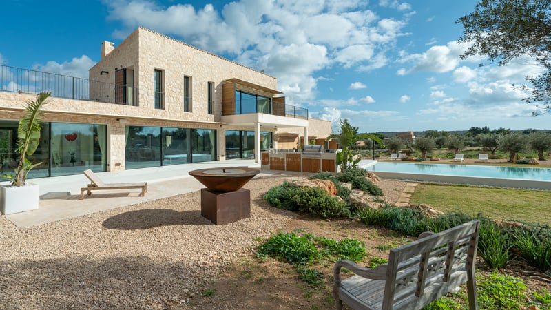 Modern tvåvåningsvilla med naturstensfasad, stora glaspartier, exklusivt utekök och designad eldstad.