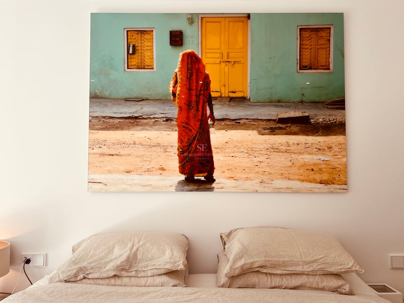 Œuvre d'art colorée au-dessus d'un lit avec des oreillers en lin neutre sur un mur blanc.