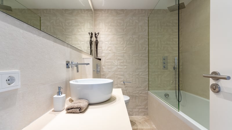 Modernes Badezimmer mit Aufsatzwaschbecken, großem Spiegel und geometrisch strukturierter Fliesenwand.