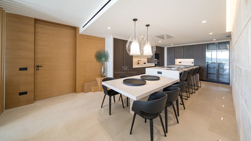 Cuisine moderne à aire ouverte avec îlot en pierre, armoires en bois sombre et suspensions design.