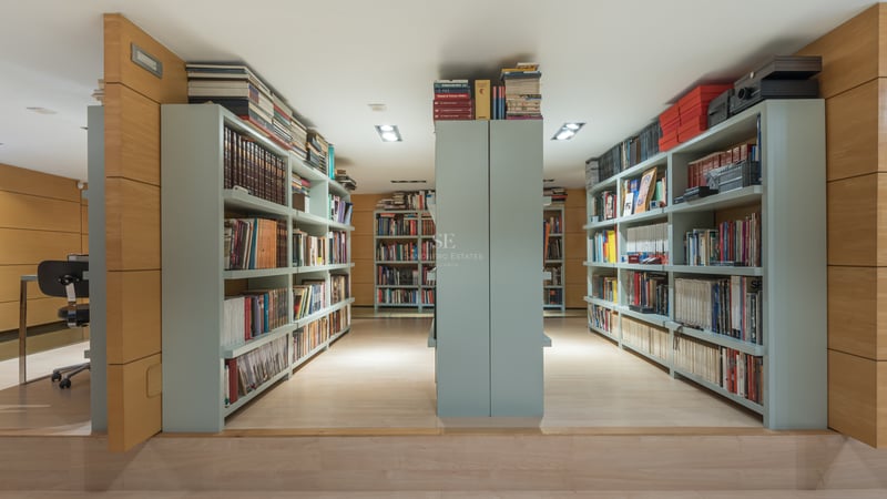 Bibliothèque moderne avec boiseries en chêne clair et étagères intégrées vert sauge.