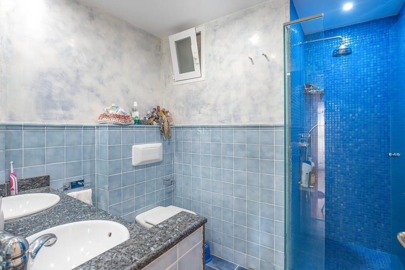 Badezimmer mit blauen Fliesen, Doppelwaschbecken aus Granit und blauer Mosaikdusche.