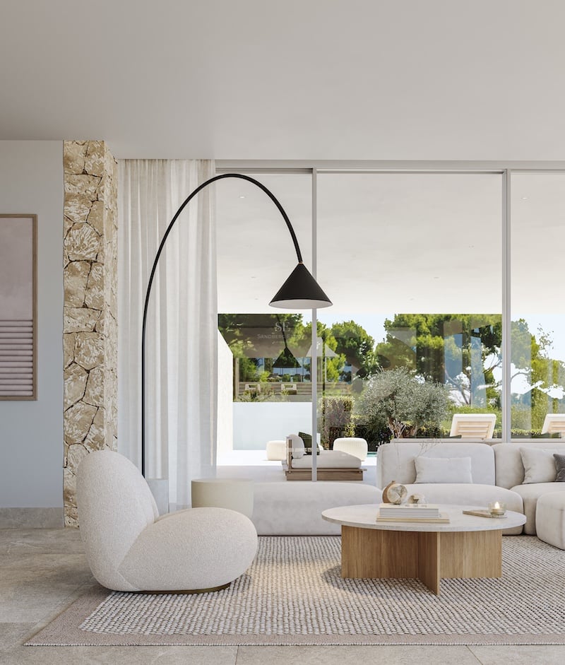Salon lumineux avec mobilier bouclé, mur en pierre naturelle et baies vitrées ouvrant sur le jardin.
