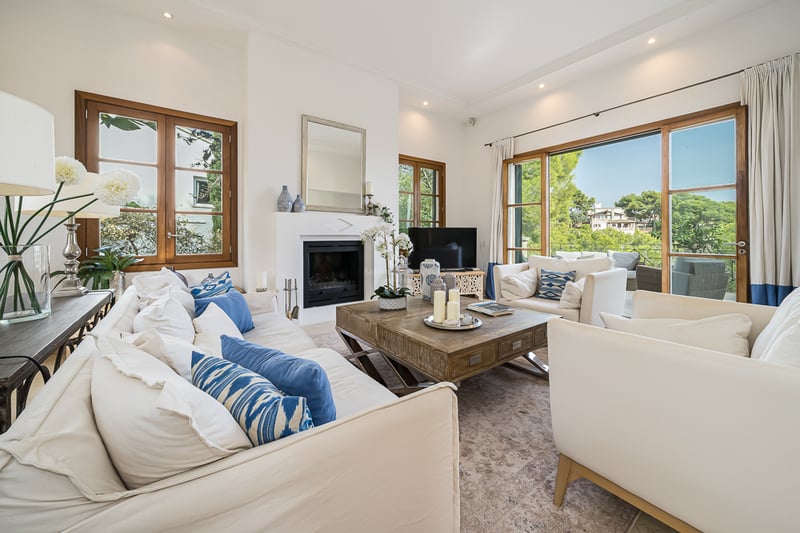 Ljust vardagsrum med vita soffor, blå detaljer, ett stort soffbord i trä och inbyggd öppen spis.