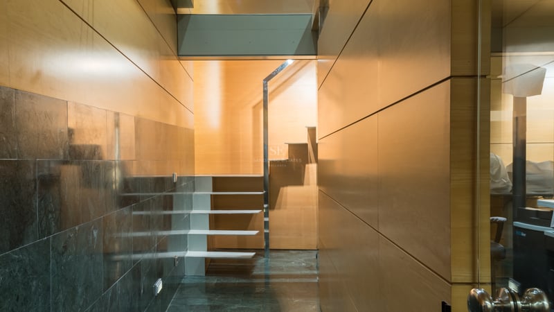Couloir intérieur moderne avec murs en panneaux de bois clair, sol en pierre sombre polie et escalier blanc flottant.