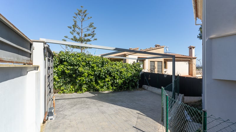 Stenlagd privat parkeringsplats med automatisk skjutgrind och en metallstomme för pergola.