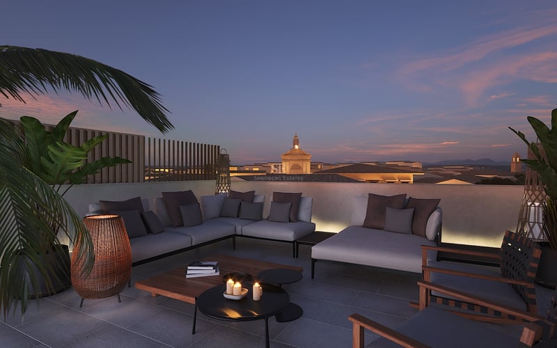 Salon de toit luxueux avec canapés gris et éclairage chaleureux surplombant une ville méditerranéenne au crépuscule.