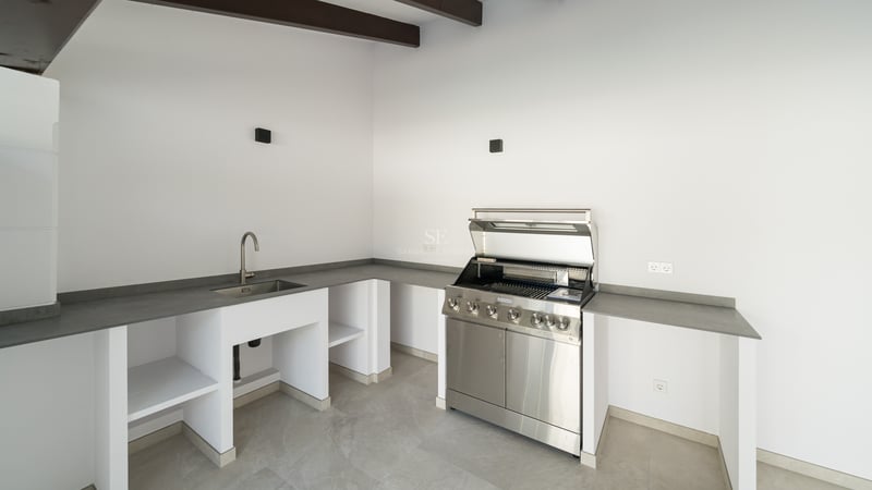 Cuisine extérieure contemporaine avec grill en inox, évier intégré et plans de travail gris.