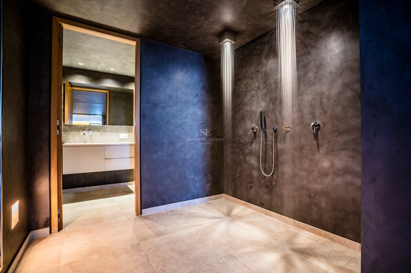 Moderne begehbare Dusche mit zwei Decken-Regenbrausen und anthrazitfarbenen Mikrozementwänden.