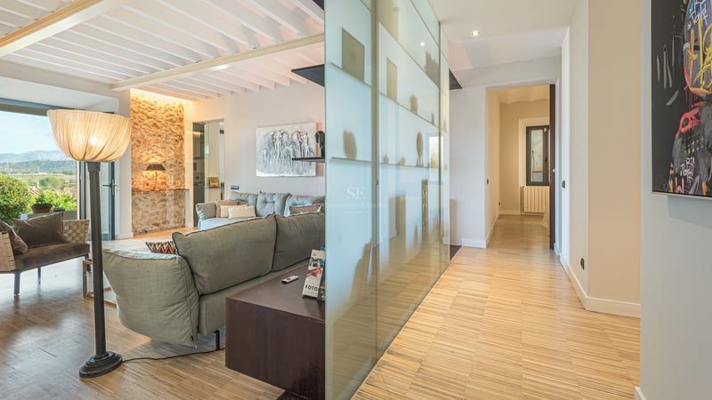 Vardagsrum med grå soffa, trägolv, stenvägg och avskärmning i frostat glas.