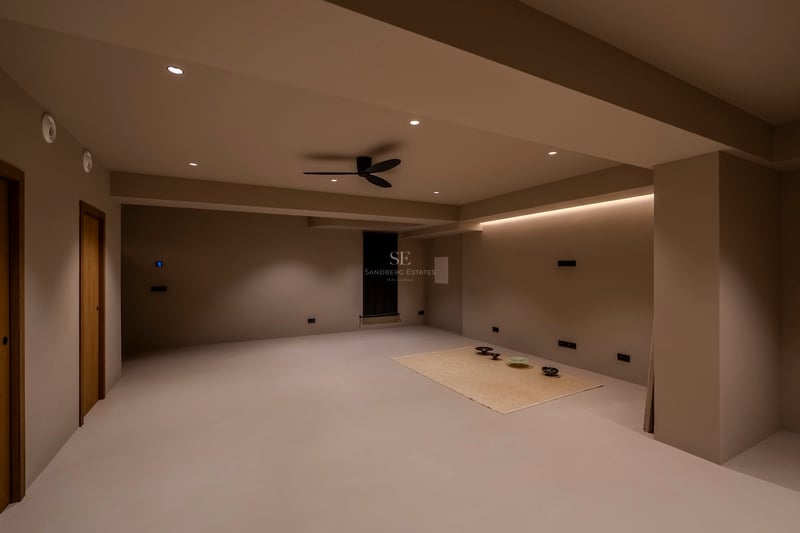 Pièce minimaliste vide avec murs beiges, éclairage LED indirect et ventilateur de plafond noir moderne.