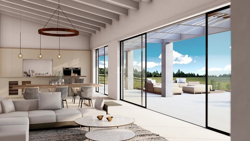 Salon lumineux avec poutres apparentes, canapés modernes et grandes baies vitrées ouvrant sur une terrasse ensoleillée.