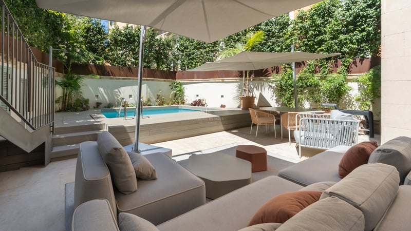 Terrasse moderne avec petite piscine, salon extérieur sous parasols et plantes verdoyantes pour l'intimité.