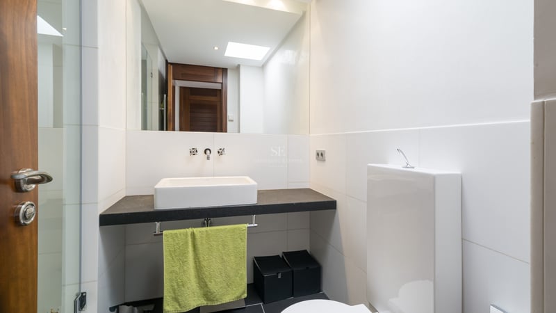 Contemporary bathroom featuring a white vessel sink on a dark stone vanity with a large wall mirror.