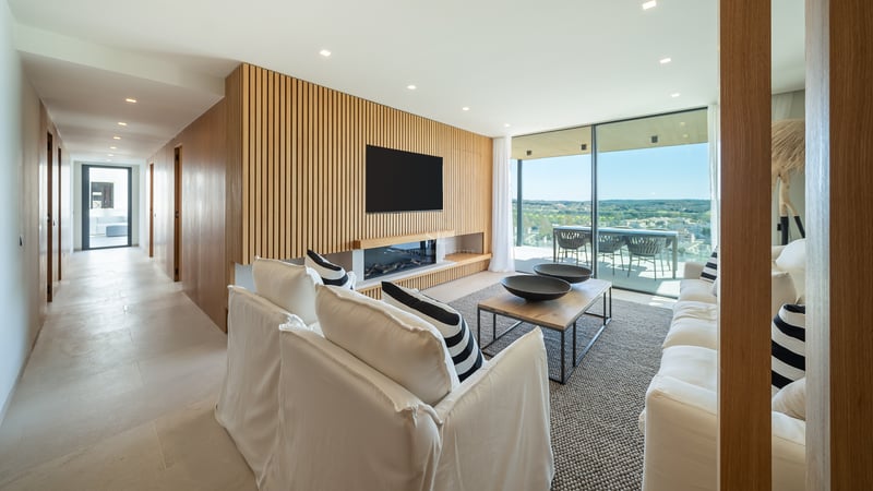 Salon moderne avec mur en bois à claire-voie, cheminée linéaire, canapés blancs et grandes baies vitrées.