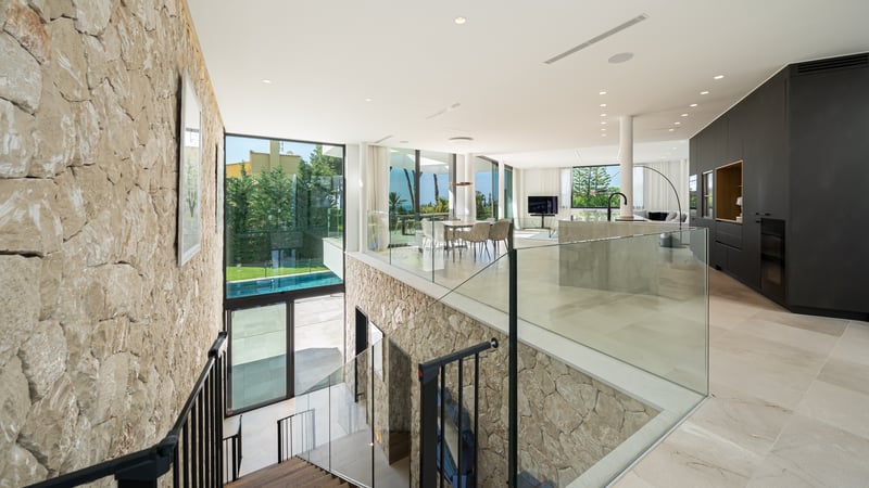 Vue en hauteur d'un salon et d'une salle à manger modernes à aire ouverte avec un mur en pierre naturelle et du verre.