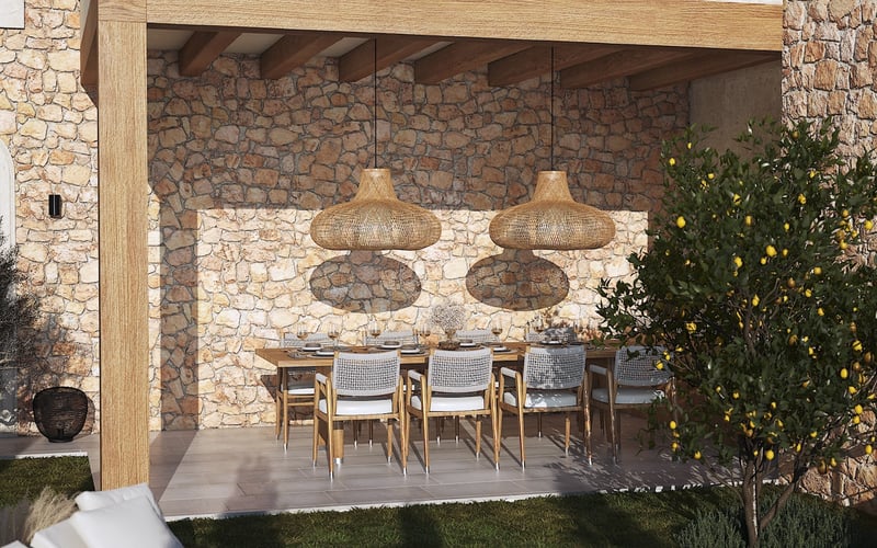 Espace repas extérieur couvert avec table en bois, suspensions en osier et mur en pierre naturelle rustique.