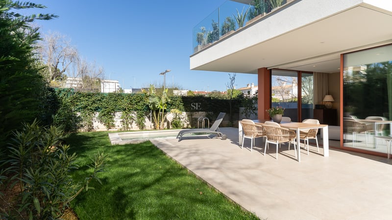 A contemporary outdoor terrace featuring a dining set, sun lounger, private lawn, and small pool under a clear blue sky.