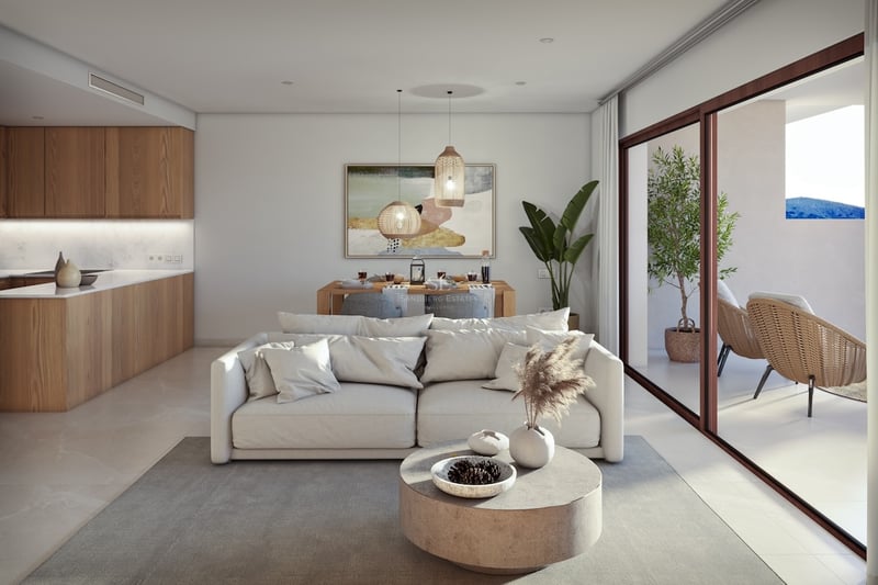 Modern living room with white sofa, stone coffee table, and large glass doors opening to a sunny terrace.