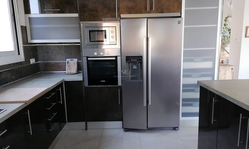 Cuisine contemporaine avec placards brillants, électroménager Bosch intégré et grand réfrigérateur en inox.