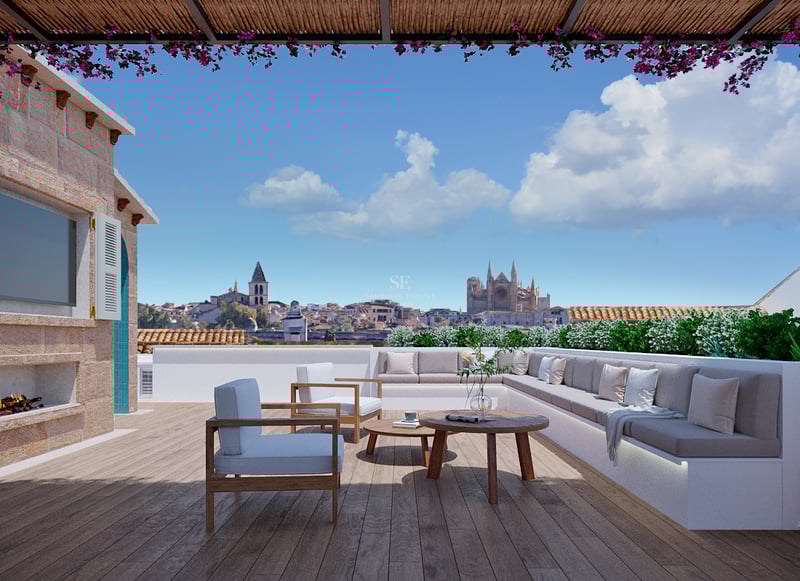 Luxury rooftop terrace with wooden deck, comfortable lounge seating, fireplace, and panoramic views of a city cathedral.