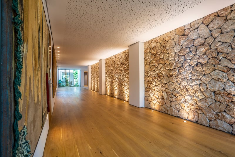 Moderner Innenflur mit strukturierter Steinwand, Bodenstrahlern und hellem Eichenparkett.