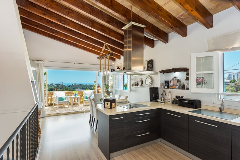 Spacious balcony with a sea view. Glass railing, light wood flooring, modern and elegant furniture. Bright and relaxing atmosphere.