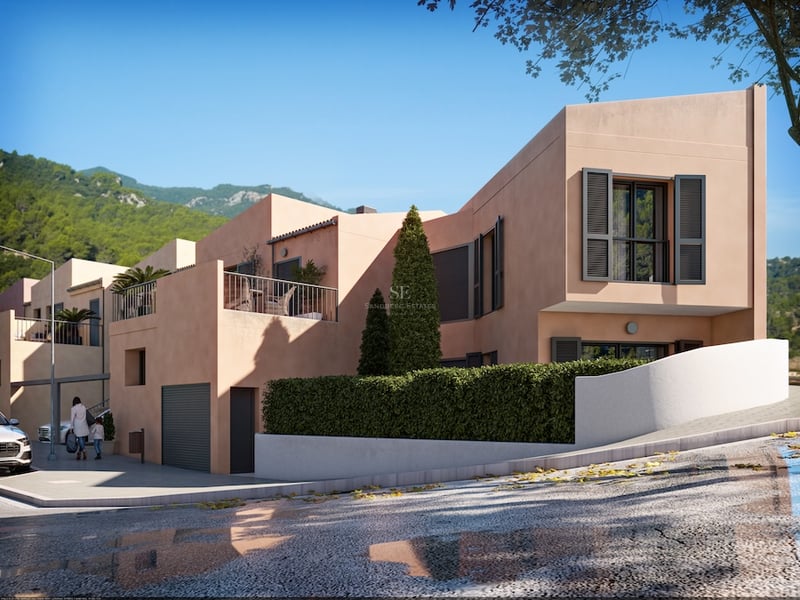 Modern persikofärgad villa med mörka fönsterluckor och terrass mot en bergig bakgrund.