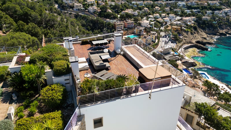 Aerial view of a modern rooftop terrace featuring wooden decking, a hot tub, lounge seating, and dining area.