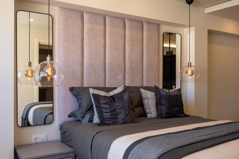 Bett mit rosa Kopfteil, hängenden Glaslampen und symmetrischen Spiegeln in einem modernen Luxusschlafzimmer.