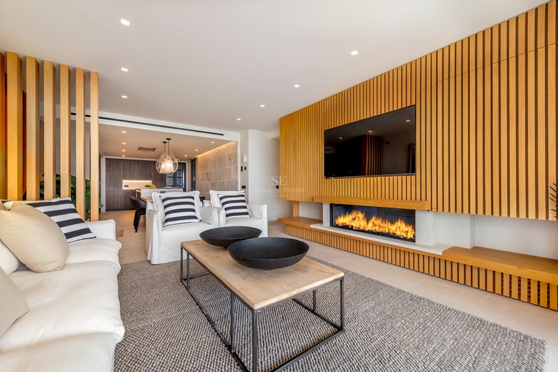 Salon moderne avec mur en tasseaux de chêne, cheminée linéaire intégrée et canapés blancs confortables.