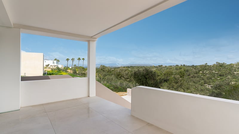 Minimalistische weiße überdachte Terrasse mit polierten Fliesen und Blick auf ein grünes Tal und Berge.