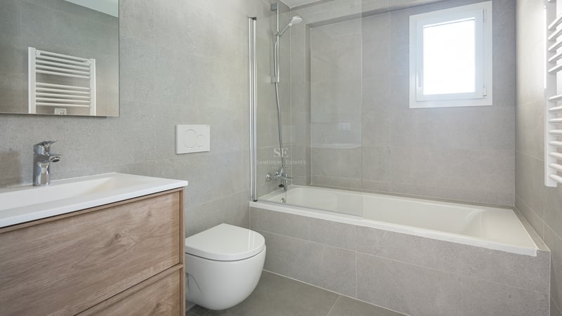 Salle de bain contemporaine avec carrelage gris effet pierre, baignoire et paroi en verre, et meuble sous vasque en chêne.