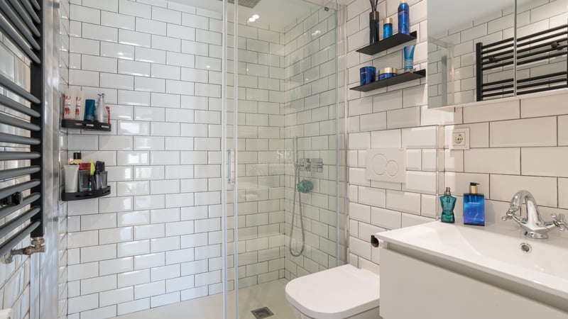 Salle de bains moderne avec carreaux de métro blancs, douche à l'italienne en verre et radiateur noir.