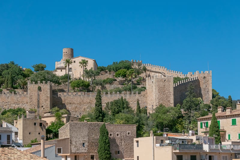 Murs et tours en pierre d'une forteresse médiévale sur une colline sous un ciel bleu dans un village majorquin.